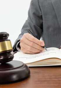 1_0000_closeup-shot-person-writing-book-with-gavel-table